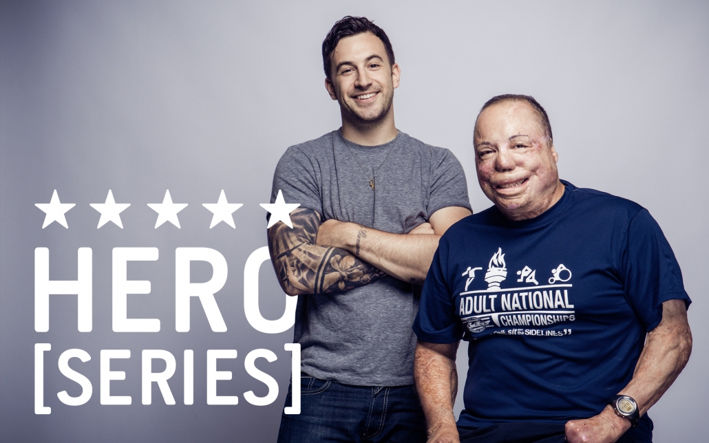 HERO Series logo with a graphic designer male with a tattoos on his arm standing next to a wounded veteran sitting on a stool